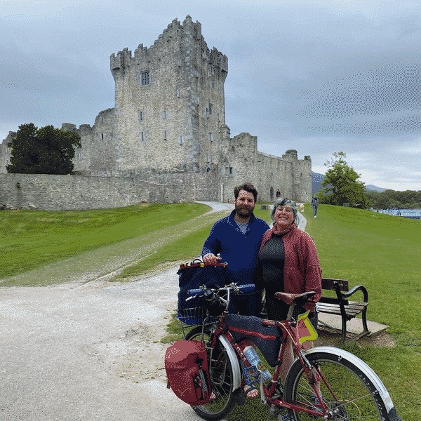 Travis and Ruby standing by a bike in front of a castle in Ireland