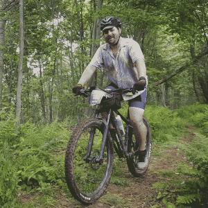 Travis riding a mountain bike through the woods from the Grinduro 2024 ride