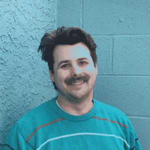 A dithered image of Travis in front of a blue-green wall